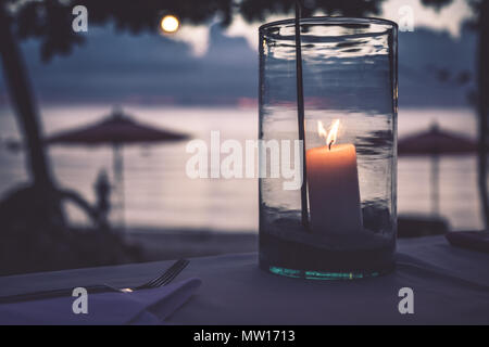 Romantische Strand Restaurant Szene Kerzen Sonnenuntergang verschwommenen Hintergrund Stockfoto
