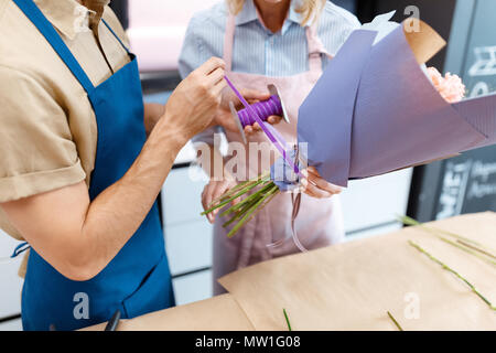 7/8 Schuß von Floristen in Schürzen arrangieren Blumenstrauß in Flower Shop Stockfoto