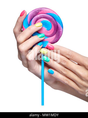 Frau hält Lollipop candy. Weibliche Finger mit hellen Grün, Gelb, Pink und Blau Nägel Maniküre. Girl's Hände auf weißem Hintergrund Stockfoto