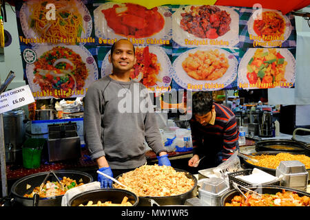 Lächelnd Anbieter verkaufen verschiedene Gerichte im Fast food in Brick Lane Market, London, England, UK. Stockfoto