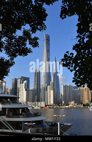 Skyline von Pudong über den Huangpu Fluss von Bäumen mit Boot im Vordergrund gerahmt, zeigen einige der höchsten Gebäude der Welt, Shanghai, China Stockfoto