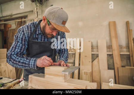 Close-up des Handwerkers Hände in Handschuhe messen Holzbrett mit Lineal und Bleistift auf der Workbench. Konzept der Holzarbeiten und Handarbeit. Stockfoto