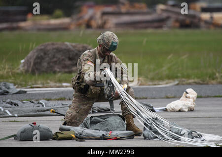 Ein Sky-Soldat aus C Company, 2. Bataillon, 503. Infanterieregiment 173rd Airborne Brigade versammelt seine Ausrüstung und verstaut seinen Fallschirm bei einem gemeinsamen Luft Betrieb und Flugplatz Anfall mit der Armee der Tschechischen Republik während des Trainings einen gemeinsamen Bereich als Teil der Übung Saber Junction 17 in Mimon, Tschechien 17. April 2017. Übung Saber Junction demonstriert die Fähigkeit der 173rd Airborne Brigade zu schnell bewegen und montieren ihre Kräfte in Zusammenarbeit mit NATO-Verbündeten, kritische Ressourcen, die es ermöglicht sichere folgende entscheidende Ausrüstung Land Luft zwingt. Stockfoto