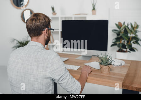 Rückansicht des Geschäftsmanns, der mit Computer am Arbeitsplatz in modernen Büro Stockfoto