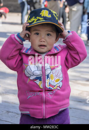 Peking, China - 29. April 2010: Summer Palace. Nahaufnahme von sehr jungen Jungen mit rosa Hemd und blauer Kappe, die er hält mit beiden Händen. Stockfoto