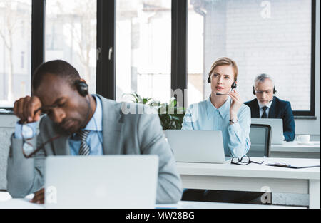 Drei multiethnischen Geschäftsleute in Headsets arbeiten mit Laptops in modernen Büro Stockfoto