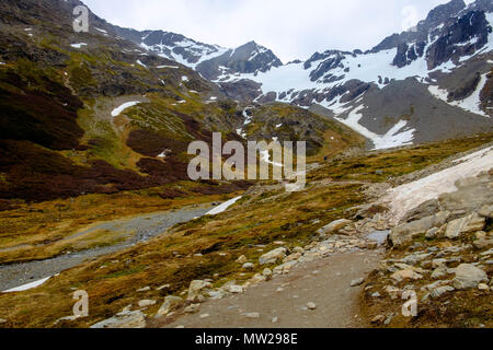 Der Wanderweg in Richtung Gletscher Martial in der Nähe von Ushuaia, Argentinien, führt durch Patches von Schnee und neben einem kleinen Bach auf einem schneebedeckten Gletscher. Stockfoto