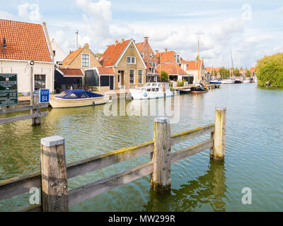 Hafen mit Booten und Kai mit historischen Häuser in der Altstadt von Makkum, Friesland, Niederlande Stockfoto