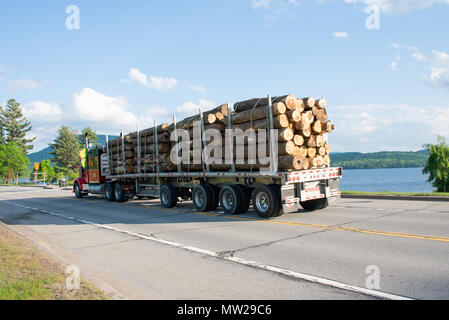 Schwer beladenen Lkw schleppen die Protokolle auf der Autobahn vorbei an Lake Pleasant log in den Adirondack Mountains, NY, USA Stockfoto