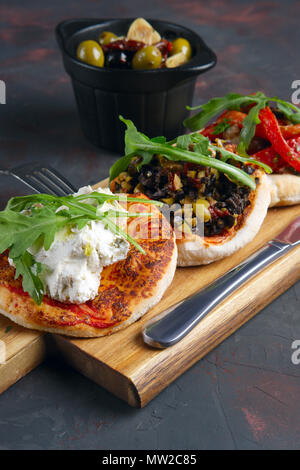 Köstliche Tapas. Kleine Sandwiches mit Ziegenkäse, gehackten Oliven und Nüssen, cured Tomaten und gebratener Paprika. Stockfoto