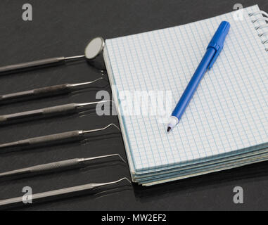 Set aus Metall Zahnarzt medizinische Geräte Werkzeuge mit Notebook und Marker. Stockfoto