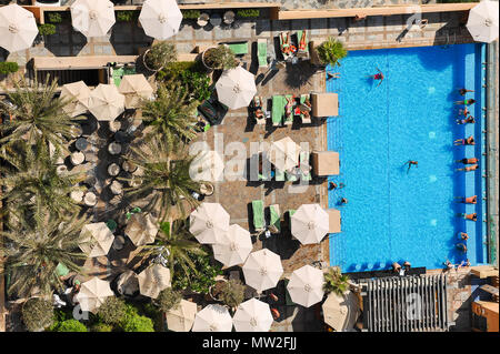 Luftbild in einem Resort Swimmingpool, mit Menschen entspannen unter Sonnenschirmen und Abkühlung im Wasser in Dubai, VAE Stockfoto