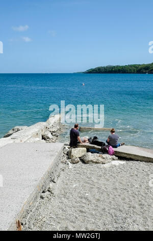 Urlauber entspannen auf dem privaten Strand Polgwidden Cove at Trebah Garten in Cornwall. Stockfoto