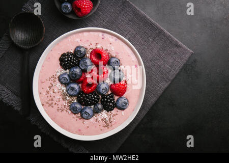 Köstlich leckeren Smoothie Schale mit Beeren auf Platte auf dunklem Hintergrund. Ansicht von oben Stockfoto