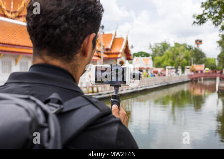 Mann backpacher Wer hält Mobiltelefon auf Gimbal Besuch in Asien an einem sonnigen Tag, Solo Reise und Ferien Konzept. Stockfoto