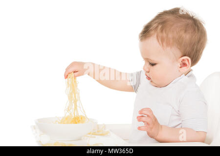 Seitenansicht des entzückenden kleinen Jungen essen Spaghetti von Hand auf weißem Hintergrund Stockfoto