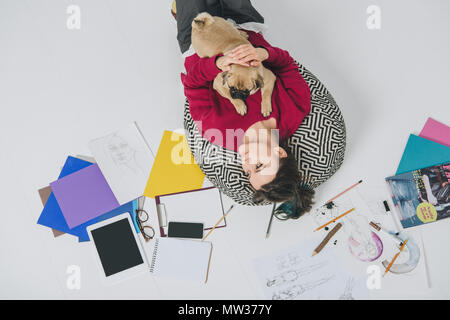 Junge Frau liegt mit Mops unter Skizzen Stockfoto
