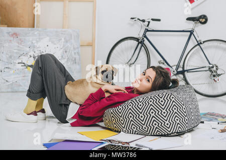 Junge Frau auf dem Boden liegend mit Mops Stockfoto