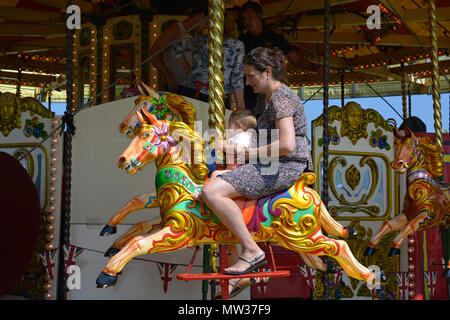 Mutter und Kind ein Pferd Reiten auf dem Karussell bei der jährlichen Sherborne Castle Country Fair, Sherbourne, Dorset, England. Stockfoto