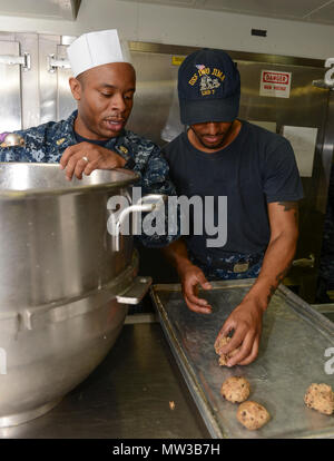 MAYPORT, Fla (27. April 2017) - Chief kulinarische Spezialist David Hargress und kulinarischen Specialist 3. Klasse Kyheim Porter pan Plätzchenteig in der Bäckerei des Amphibious Assault ship USS Iwo Jima (LHD 7) in Vorbereitung der Mayport Navy Exchange Cupcake Kriege. Iwo Jima führt derzeit eine geplante Wartung Verfügbarkeit. Stockfoto