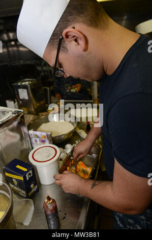 MAYPORT, Fla (27. April 2017) - Kulinarische Specialist 2. Klasse Tandy Hollingsworth mischt die Glasur in der Bäckerei des Amphibious Assault ship USS Iwo Jima (LHD 7) in Vorbereitung der Mayport Navy Exchange Cupcake Kriege. Iwo Jima führt derzeit eine geplante Wartung Verfügbarkeit. Stockfoto