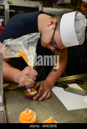 MAYPORT, Fla (27. April 2017) - Kulinarische Specialist 2. Klasse Tandy Hollingsworth gilt Glasur zum Seitenanfang cupcakes in der Bäckerei des Amphibious Assault ship USS Iwo Jima (LHD 7) in Vorbereitung der Mayport Navy Exchange Cupcake Kriege. Iwo Jima führt derzeit eine geplante Wartung Verfügbarkeit. Stockfoto