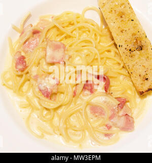 Spaghetti Carbonara Nudeln Nudeln mit Schinken, Speck, Käse und Brot auf einem weißen Teller in Abendessen Zeit Stockfoto