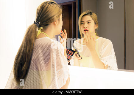 Schöne asiatische Jugendmädchen Anwendung Lippenstift ihren Mund vor dem Spiegel im Badezimmer Stockfoto