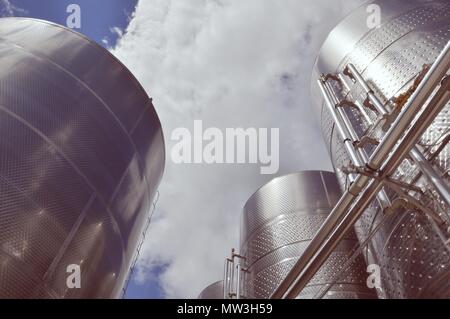 Großen Stahltanks für Wein Reifung, bewölkter Himmel Hintergrund, Weingut moderne Ausrüstung, Ansicht von unten, Retro Stil Stockfoto