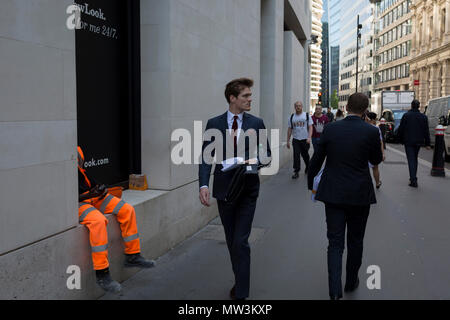 Die Beine von einem Handwerker tragen Hi-vis und eine Stadt Geschäftsmann im Anzug auf der Lombard Street in der City von London, Financial District aka der Hauptstadt der Square Mile, die am 15. Mai 2018 in London, Großbritannien. Stockfoto