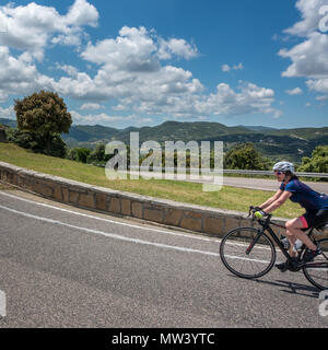 Weibliche Radfahrer mit dem Fahrrad durch die schöne Landschaft von Sardinien auf dem letzten Hügel und Haarnadelkurve zu Luogosanto. Stockfoto