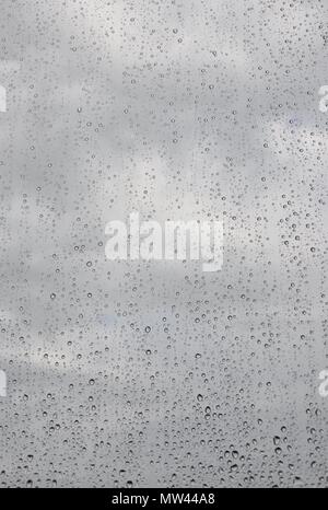 Regentropfen auf transparente Fenster mit bewölktem Himmel Hintergrund, Nahaufnahme, Copyspace Stockfoto