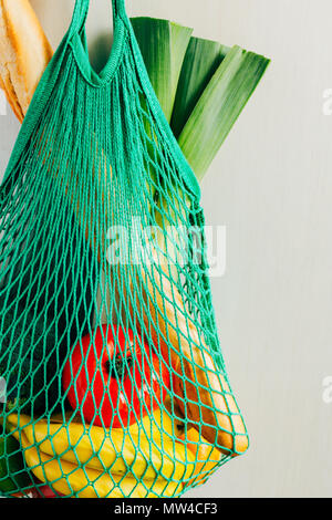 Grüne string Einkaufstasche mit Gemüse, Obst und Brot hängen an einem Haken in der Küche. Close Up. Stockfoto