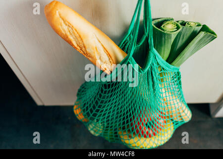 Grüne string Einkaufstasche mit Gemüse, Obst und Brot hängen an einem Haken in der Küche Stockfoto