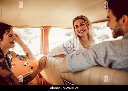 Drei junge Freunde Reisen von einem alten Auto. Kleine Gruppe von jungen Menschen und Frauen in einen Road Trip zu gehen. Stockfoto