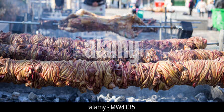 Kokoretsi, kokorech, kokorec und Lamm, Schaf am Spieß Grillen im Freien über holzkohlen Feuer. Nahaufnahme, verschwommene Menschen und street Hintergrund, Ban Stockfoto