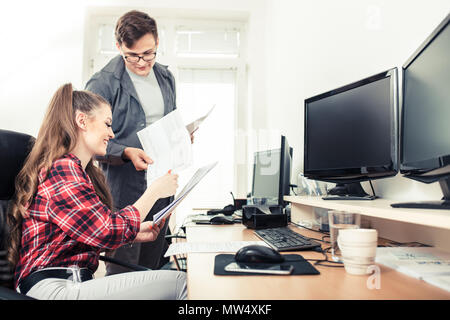Lächelnd arbeitenden Kollegen und gemeinsame Nutzung von Dokumenten in einem Schreibtisch im Büro Stockfoto