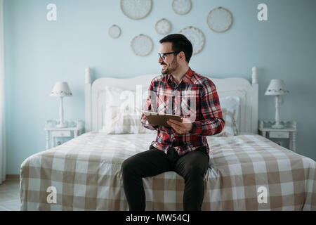 Stattlicher Mann mit digitalen Tablet im Schlafzimmer Stockfoto