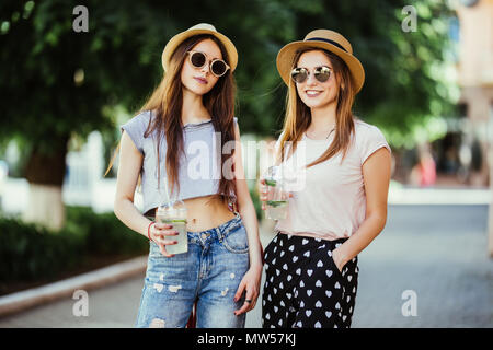 Zwei Mädchen Freundinnen trinken Sommer kalte Getränke auf der Straße Stockfoto