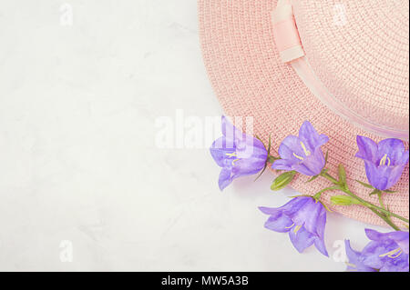 Stroh Hut mit schönen Blumen Blumenstrauß lila Blüten. Pastellfarben Hintergrund, flatlay. Stockfoto