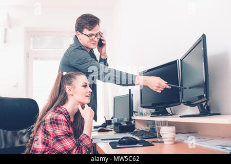 Mitarbeiter am Schreibtisch sitzen, wenn Sie mit einem Desktop Computer und Diskutieren über das Projekt im Büro. Stockfoto
