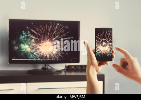 Mann mit Smartphone an einen TV Video zu Hause angeschlossen. Übertragen Sie Videos vom Telefon auf den TV-Bildschirm. Moderne Geräte. Die Informationsübertragung zwischen Dev Stockfoto