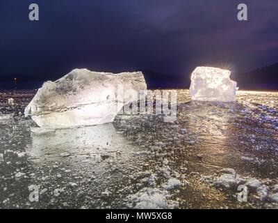 Shining faltige Oberfläche gebrochenem Eis, frische eisige Stücke auf flachen frost Boden. Bunte winter Sonnenuntergang. Stockfoto