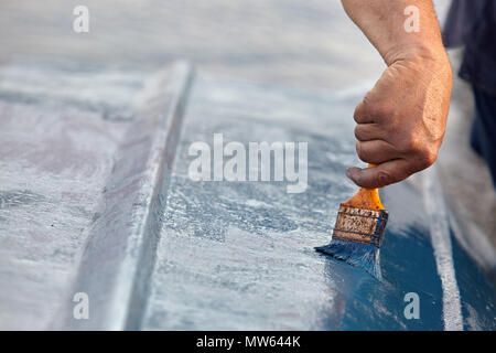 Mann Malerei Boot. Detailansicht von Hand mit einem Pinsel mit blauer Farbe. Stockfoto