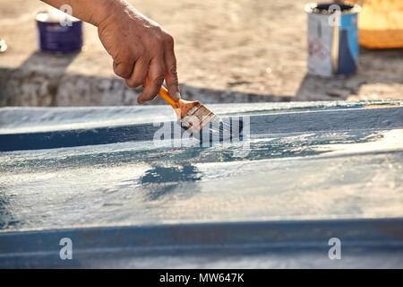 Mann Malerei Boot. Detailansicht von Hand mit einem Pinsel mit blauer Farbe. Stockfoto