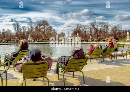 Menschen sitzen auf Stühlen entspannen in der Wintersonne rund um das Grand Bassin Rond im Jardin des Tuileries, Paris, Frankreich Stockfoto