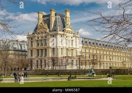 Menschen, Entspannung in der Wintersonne im Jardin des Tuileries mit Pavillon de Marsan Teil des Louvre Museum im Hintergrund, Paris Stockfoto