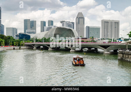 Eine Kreuzfahrt Boot wie die twakows Fahrt durch die berühmten Singapore River bekannt. Das Gebäude an der Rückseite ist die berüchtigte Theater an der Bucht, Esplanade. Stockfoto