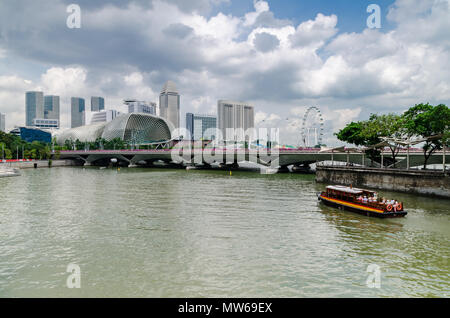 Eine Kreuzfahrt Boot wie die twakows Fahrt durch die berühmten Singapore River bekannt. Das Gebäude an der Rückseite ist die berüchtigte Theater an der Bucht, Esplanade. Stockfoto