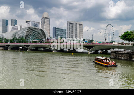 Eine Kreuzfahrt Boot wie die twakows Fahrt durch die berühmten Singapore River bekannt. Das Gebäude an der Rückseite ist die berüchtigte Theater an der Bucht, Esplanade. Stockfoto